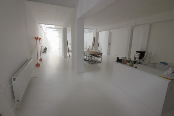 Licht en minimalistisch ingericht interieur van een open woonruimte aan de Graaf Florisstraat met keuken, eettafel en werkplekken.